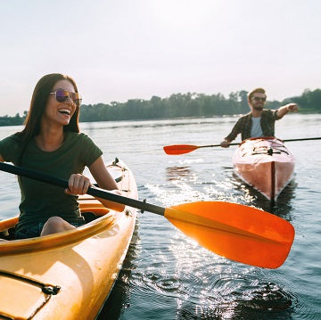 Beautiful young couple kayaking on lake together and smiling