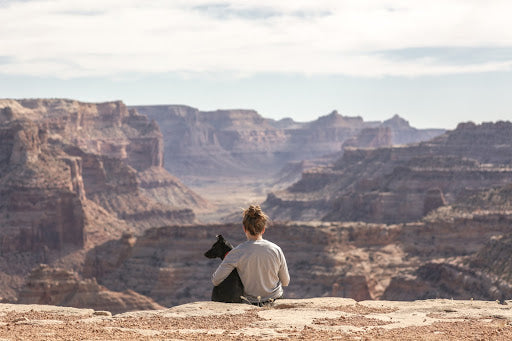 Woman and her dog sitting on the edge of a cliff