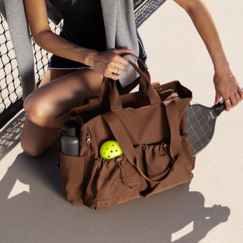 Women wearing blue backpack running across tennis court with a tennis racquet