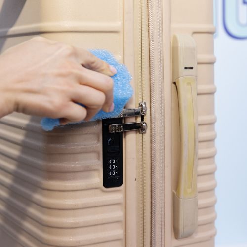 Beige Suitcase on the floor next to a wooden door and white high heels 