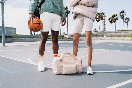 Male and female athlets on the playgeound with sport bags