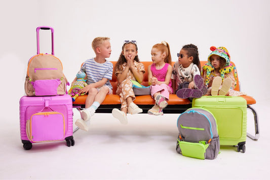 Group of children sitting on an orange couch with kids travel suitcases and bags in front of them