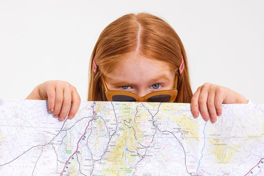 Girl with red hair and orange sunglasses looking over a road map