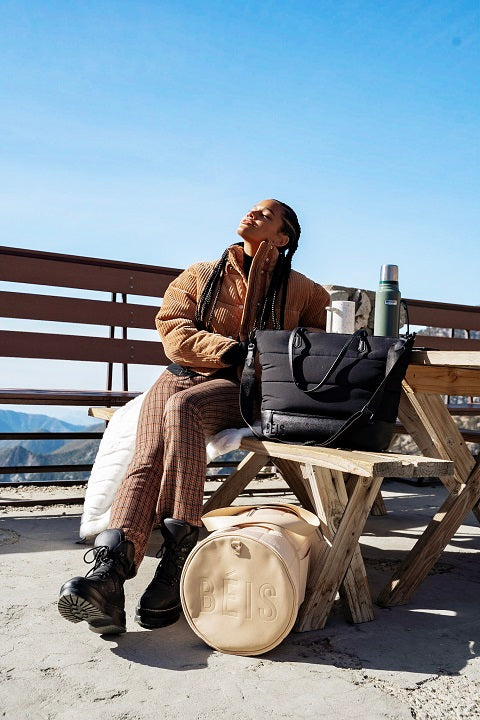 Relaxed woman sitting on a bench with travel bags around her