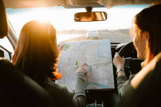 Two friends in a car, looking at the road map