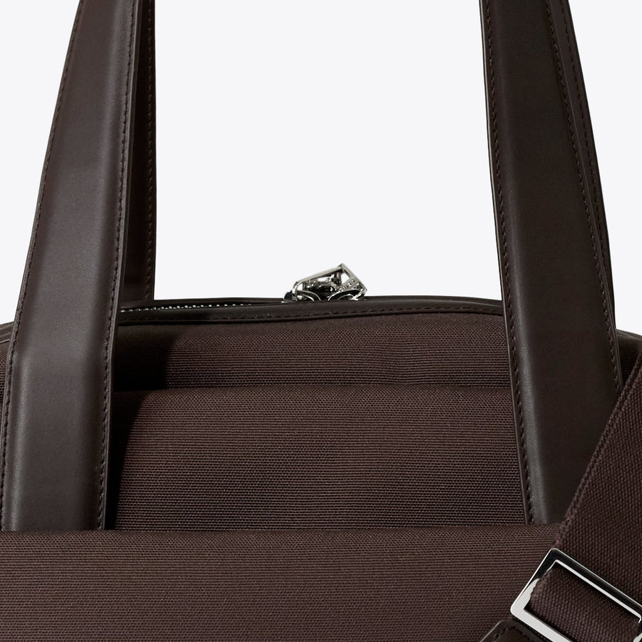 Brown duffel bag with a shoulder strap on a white background