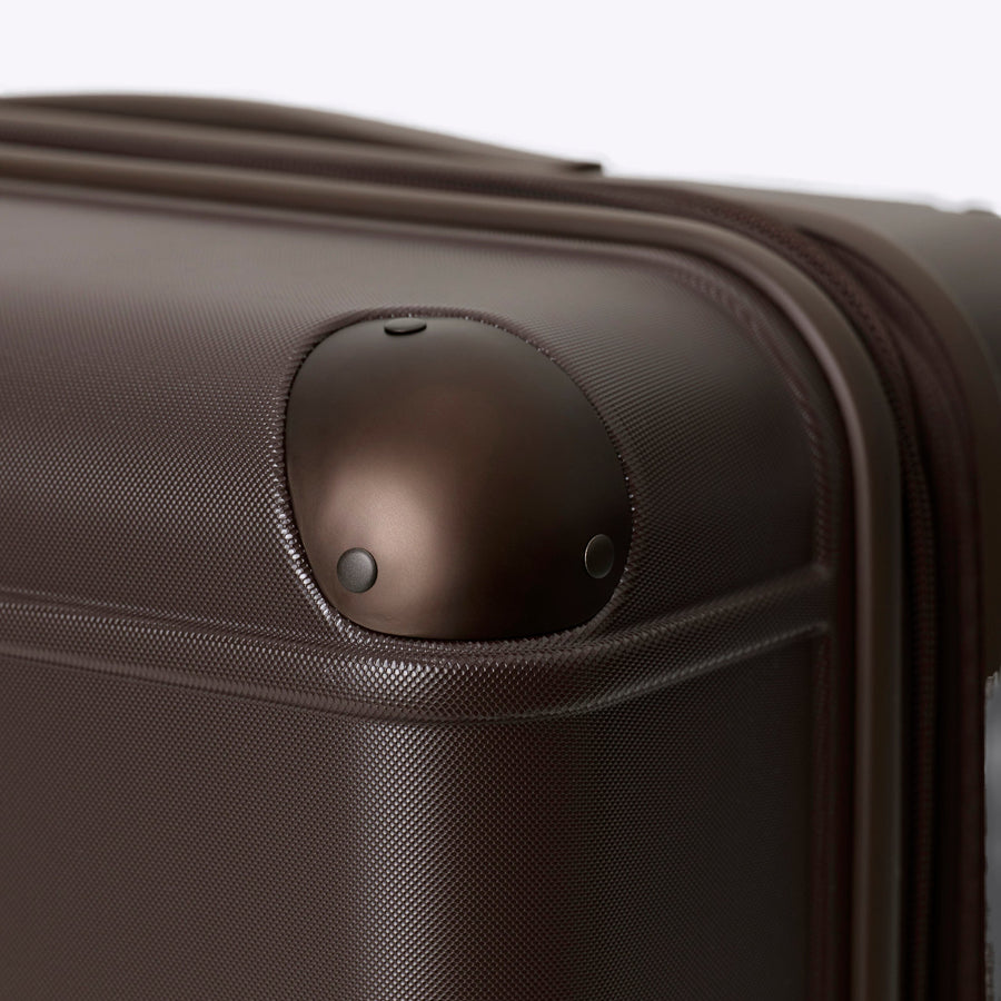 Brown suitcase with a visible wheel on a white background