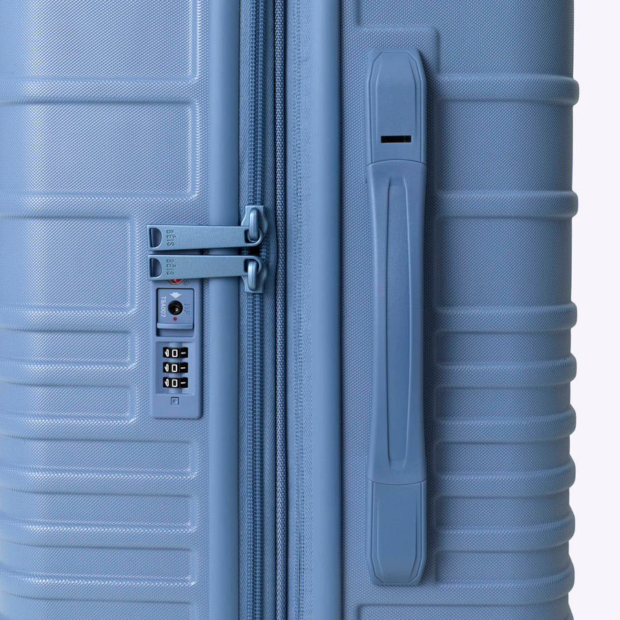 Blue suitcase with a handle and combination lock on a white background