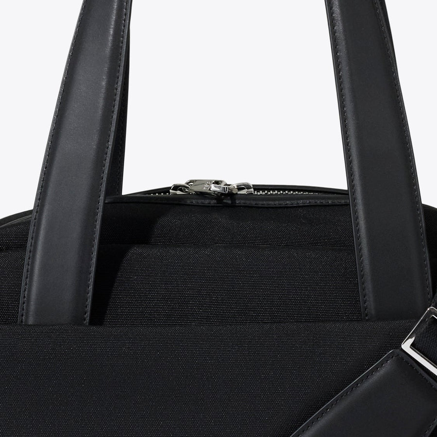 Black handbag with a shoulder strap on a white background