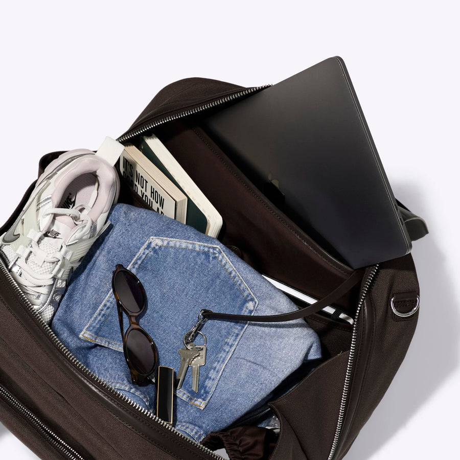 Black handbag with denim item and money on a white background
