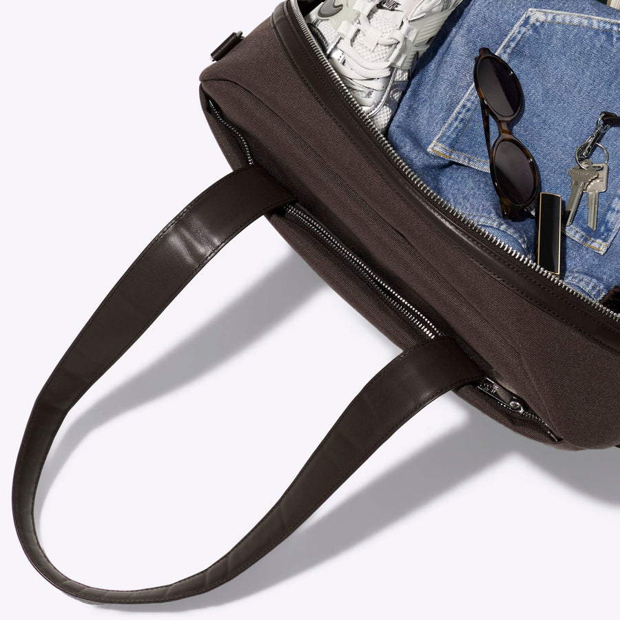 Black handbag with denim item and money on a white background