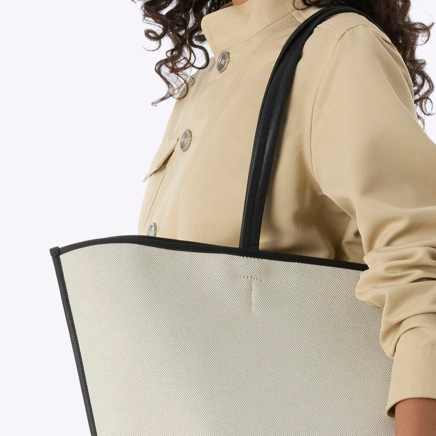 Woman holding a large beige tote bag on a white background