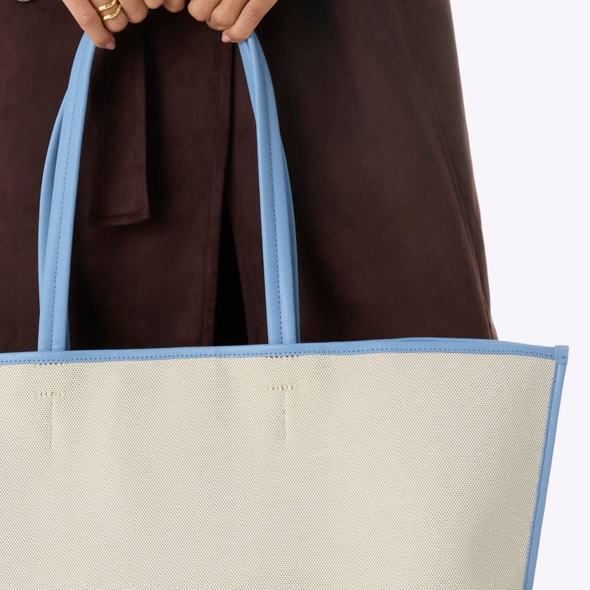 Woman holding a large tote bag against a white background