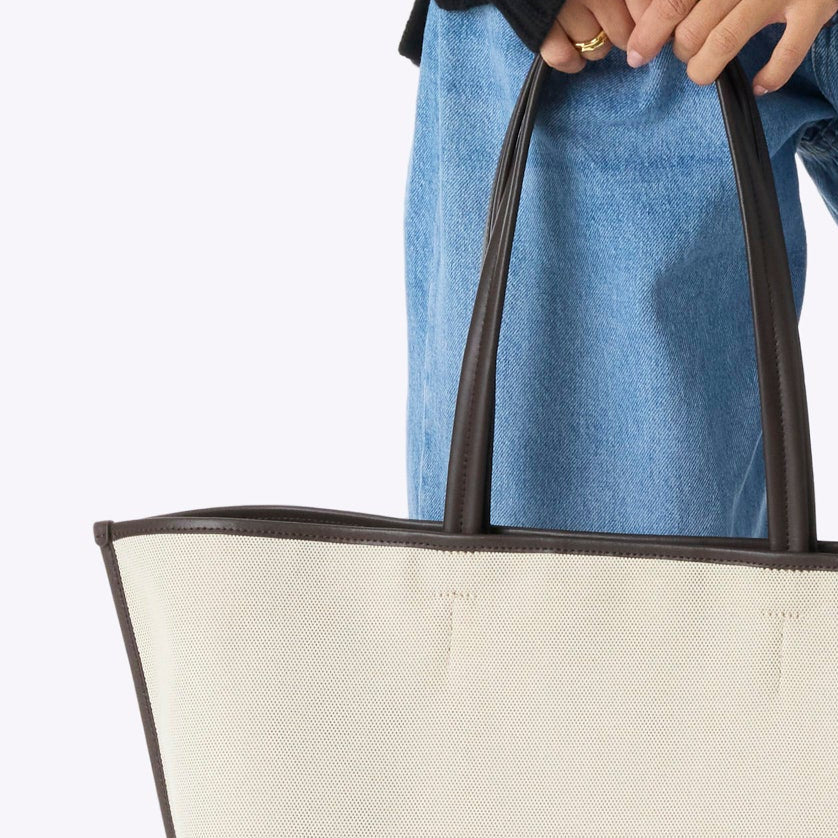 Woman holding a white tote bag against a white background