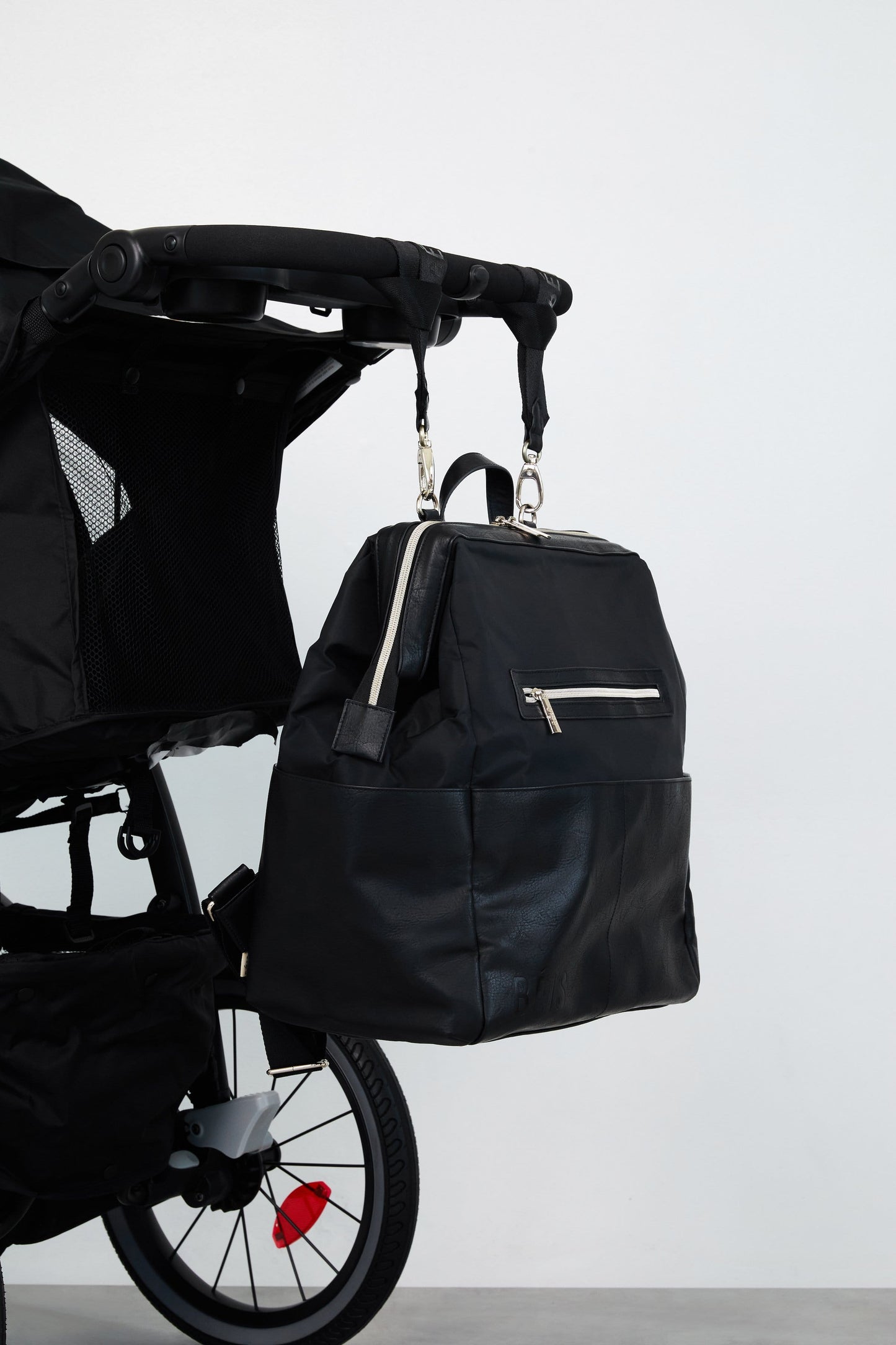 The Diaper Bag Backpack in black handing on a black stroller