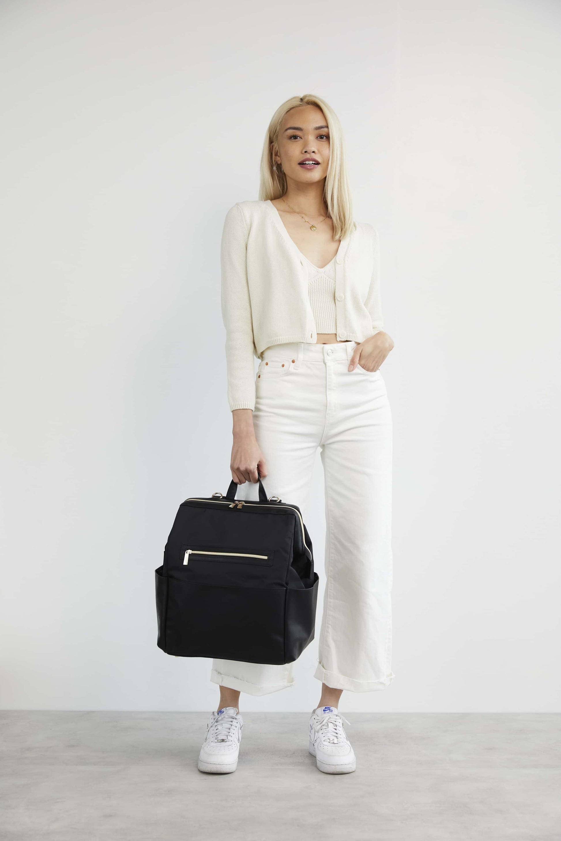 Model in white clothing holding the Diaper Bag Backpack baby bag in black