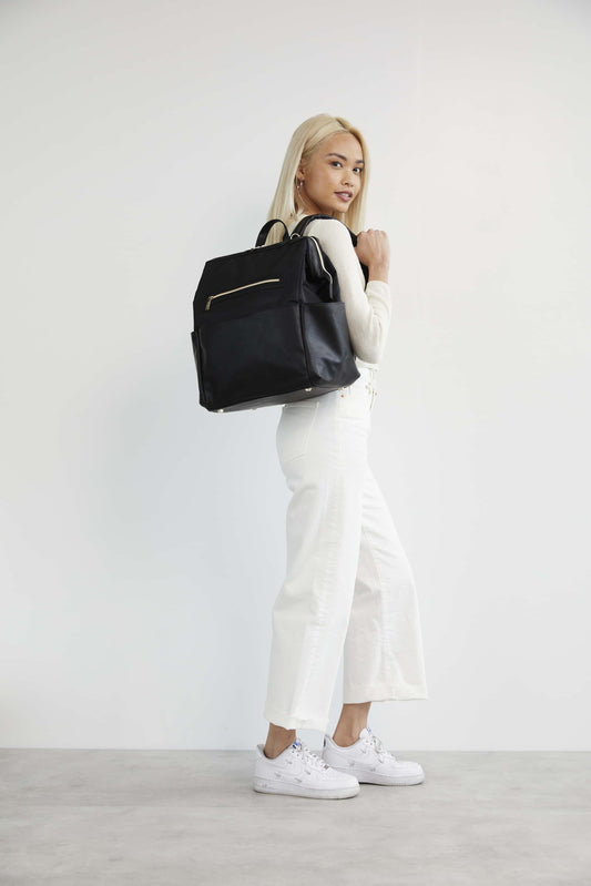 Model in white clothing holding the Diaper Bag Backpack in black over her shoulder